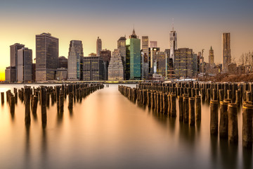 Long exposure of the Lower Manhattan skyline at sunset with an old Brooklyn pier in the foreground