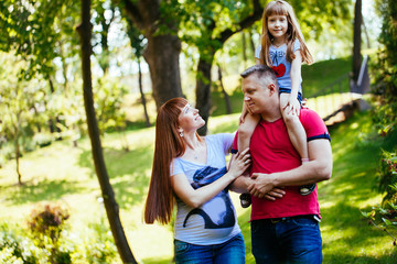 Fototapeta premium A young family, a pregnant mother, father, daughter