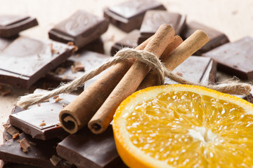 Chocolate with cinnamon sticks and orange slice, selective focus