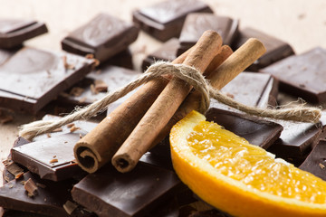 Chocolate with cinnamon sticks and orange slice, selective focus