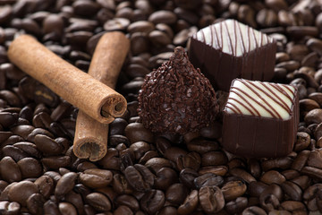 Chocolate with cinnamon sticks on coffee background, selective f