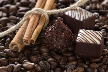 Chocolate with cinnamon sticks on coffee background, selective f