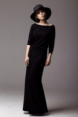 Naklejka premium Full length shot of a woman in long black dress and hat