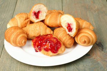 Croissants with jam on a plate on wooden background