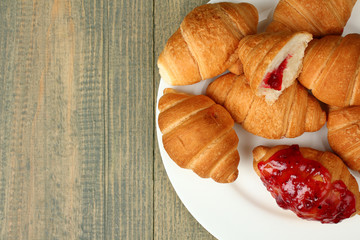 Croissants with jam on a plate on wooden background
