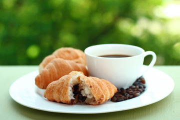 Delicious croissants on a plate with coffee in the background of nature