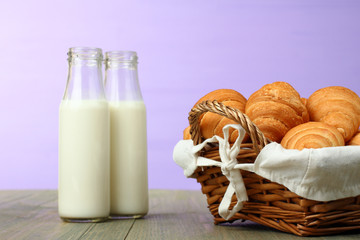 Croissants in a basket and a glass of milk on wooden background