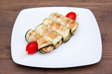 Eggplant rolls with stuffing and tomato on wooden table