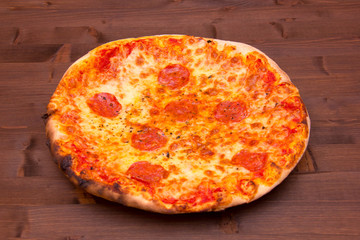 Round pizza with salami on wooden table