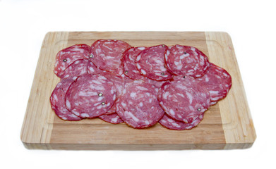 Slices of salami on cutting board on white background