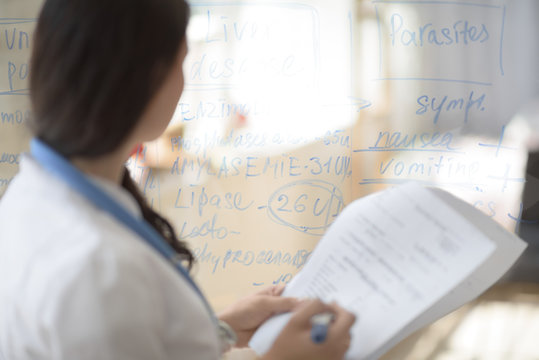 Doctor Writing Patient Test Results On Board