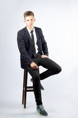 A young boy, brunette with short hair, a student in a black suit