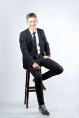 A young boy, brunette with short hair, a student in a black suit