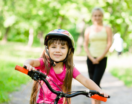 mom and daughter ride bikes in the forest