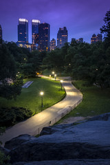 New York skyline seen from an alley in Central Park standing up on a big rock at night © Victor Moussa