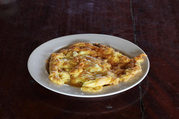 Thai omelet in dish on wooden table