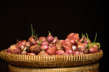 shallot bulbs in a basket on black bakground