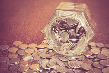 Coins spilling out of a glass bottle with filter effect retro vi