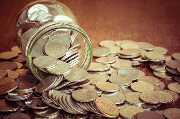 Coins spilling out of a glass bottle with filter effect retro vi