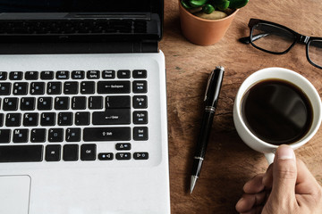 Laptop and cup of coffee on old wooden table