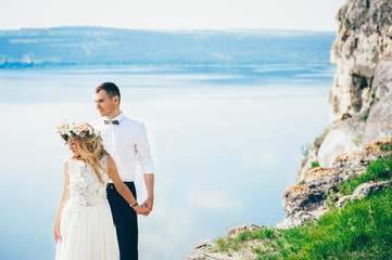 Fototapeta na wymiar beautiful young couple posing on the rock near the lake