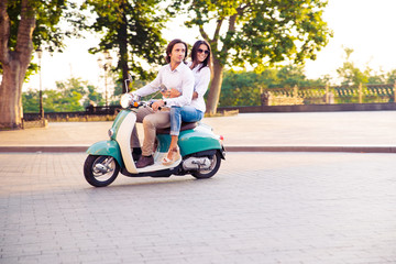 Sideview of a trendy couple riding a scooter in the morning © Drobot Dean