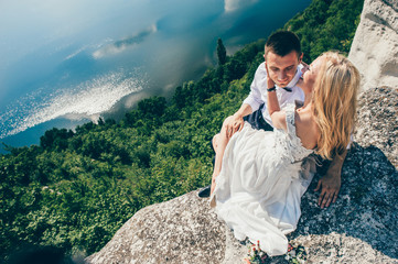 Naklejka premium beautiful young couple posing on the rock near the lake