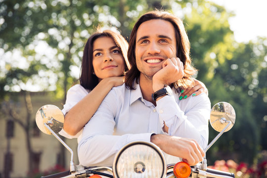 Fototapeta Happy thoughtful couple on scooter looking up