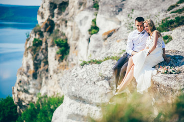 Naklejka premium beautiful young couple posing on the rock near the lake