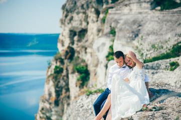 Fototapeta premium beautiful young couple posing on the rock near the lake