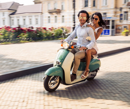Happy couple riding on a scooter