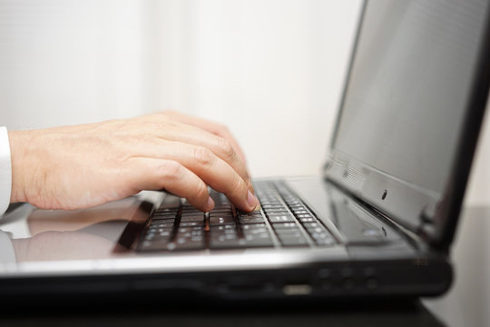 person is typing on laptop keyboard