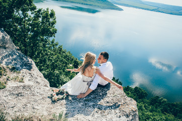 beautiful young couple posing on the rock near the lake