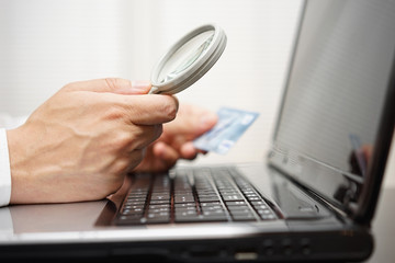 businessman is using magnifying glass  when making online paymen