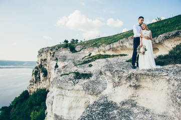 beautiful young couple posing on the rock near the lake