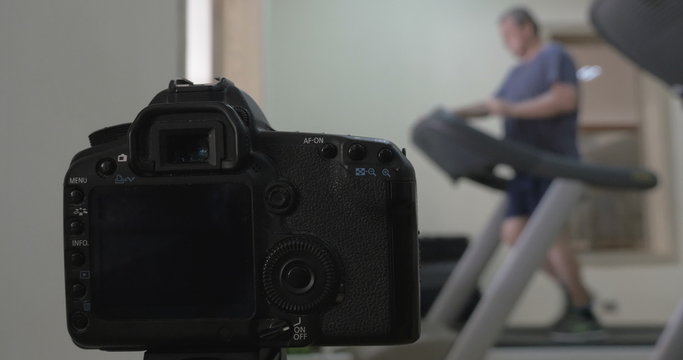 Camera making shots of man running on treadmill