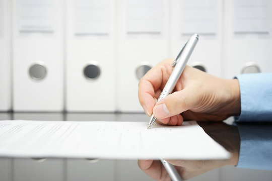 businessman is signing contract with binders in background