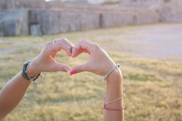 Heart shape made of girls hands in an old fortres