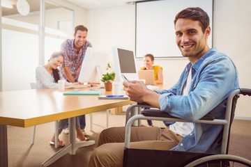 Creative businessman in wheelchair holding a phone