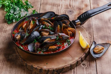 Crédence de cuisine en verre imprimé Crustacés oyster mussels in red sauce in a frying pan
