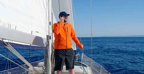 Papier Peint photo Lavable Naviguer Man sailing with sails out on a sunny day and talking on the phone