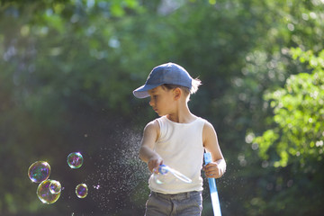 Kleiner süßer Junge spielt mit Seifenblasenschwert draussen im Park bei Sonnenschein. Platz für...