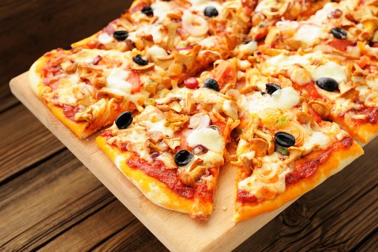 Al funghi pizza with olives cut in sectors on wooden board