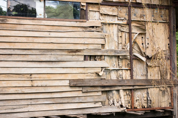 Wooden slat wall of an old house are peeling off due to none of care and maintenance.