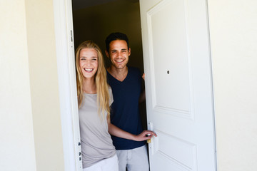 happy young couple man and woman opening door of their new home entrance