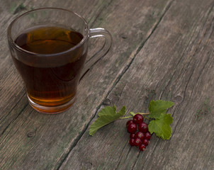 прозрачная кружка чая и смородина на ветхом столе