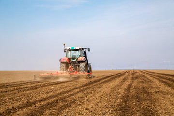 Obraz premium Farmer in tractor preparing land with seedbed cultivator