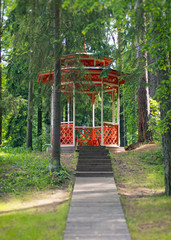 Red wooden gazebo in the forest.