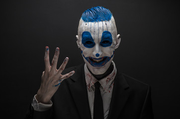 Terrible clown and Halloween theme: Crazy blue clown in black suit isolated on a dark background in the studio