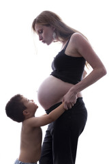 Mamá besando a su hijo abrazado a su barriga embarazada